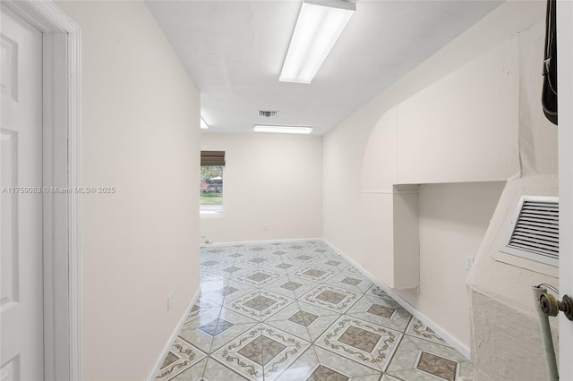hall featuring baseboards and light tile patterned flooring
