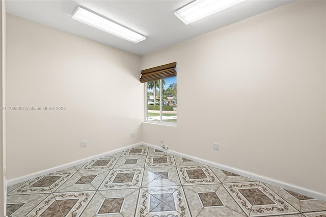 spare room featuring light tile patterned floors and baseboards