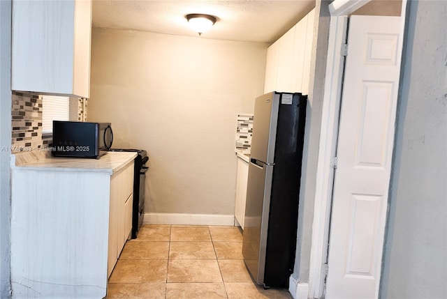 kitchen featuring light tile patterned floors, white cabinetry, light countertops, backsplash, and black appliances