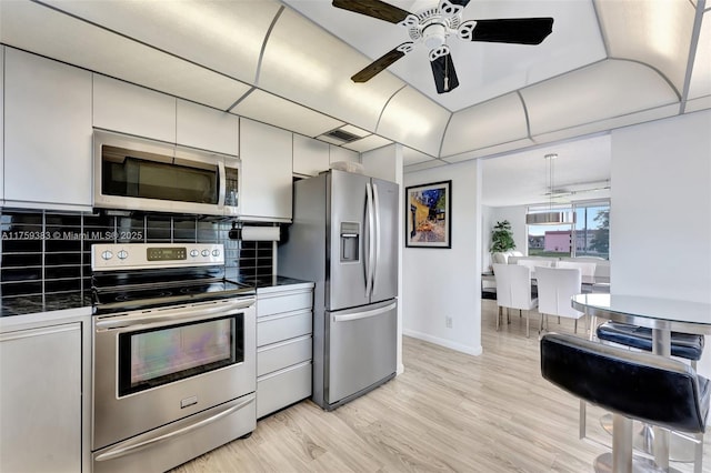 kitchen with stainless steel appliances, visible vents, light wood-style floors, tile counters, and decorative backsplash