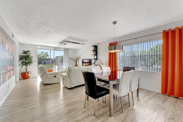 dining room featuring a textured ceiling, baseboards, and light wood-style floors