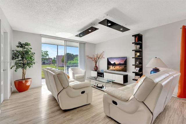 living area with a wall of windows, a textured ceiling, and light wood finished floors