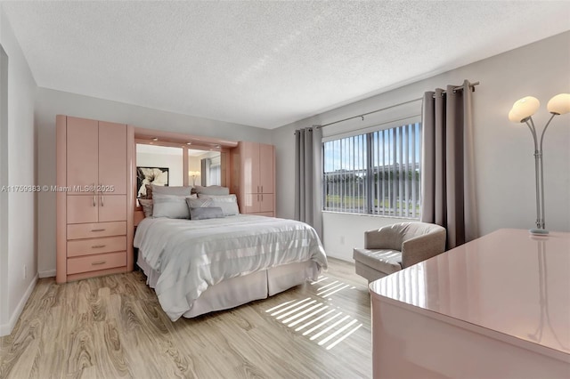 bedroom with a textured ceiling and light wood finished floors