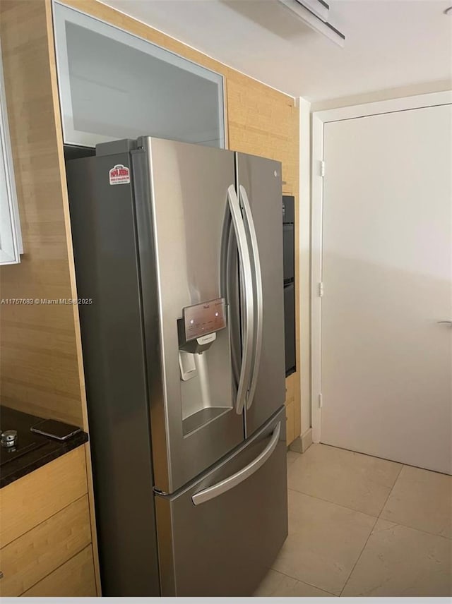 kitchen with light brown cabinetry, stainless steel fridge, and light tile patterned floors