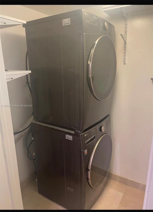 clothes washing area featuring laundry area, stacked washer / dryer, and baseboards