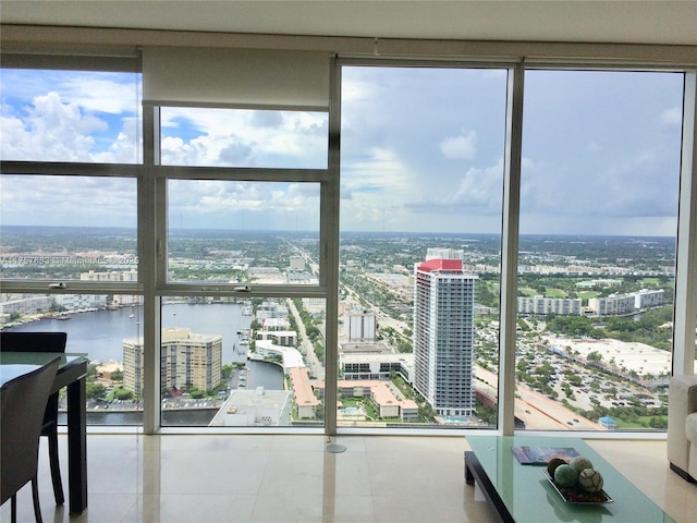 doorway with floor to ceiling windows, a water view, tile patterned flooring, and a city view