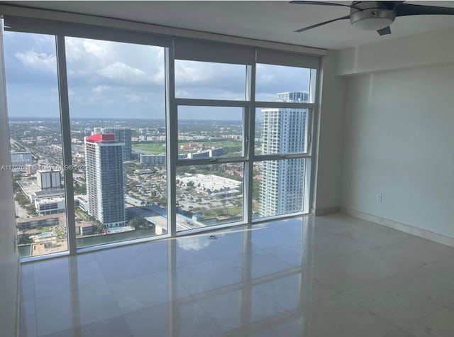 empty room with baseboards, floor to ceiling windows, plenty of natural light, and a city view