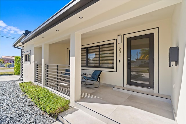 property entrance featuring a porch and stucco siding