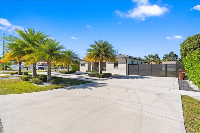 view of property hidden behind natural elements featuring a gate, driveway, and stucco siding