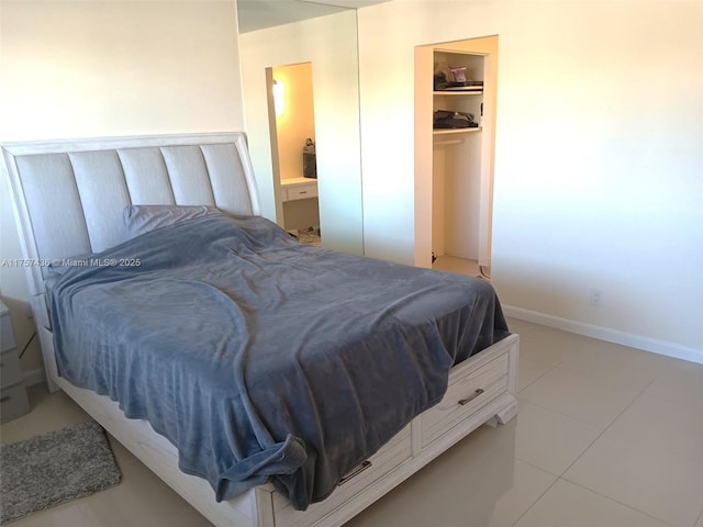 bedroom with a closet, connected bathroom, a spacious closet, and baseboards