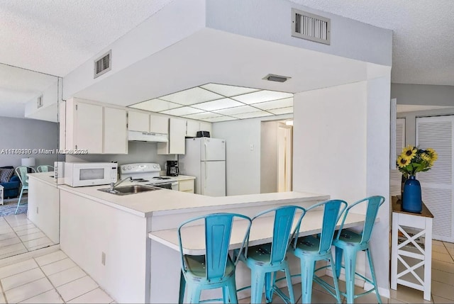 kitchen featuring white appliances, a sink, visible vents, and under cabinet range hood