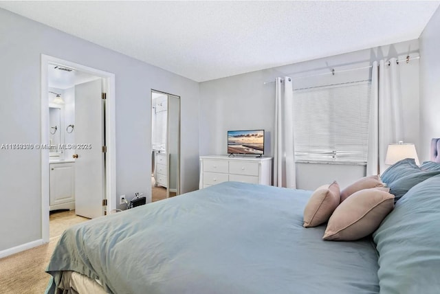 bedroom with light carpet, a textured ceiling, baseboards, and ensuite bathroom