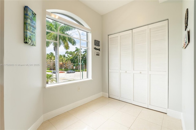 unfurnished bedroom featuring a closet, baseboards, and light tile patterned floors