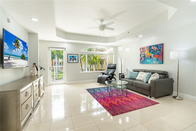 living room with light tile patterned floors, a raised ceiling, and baseboards