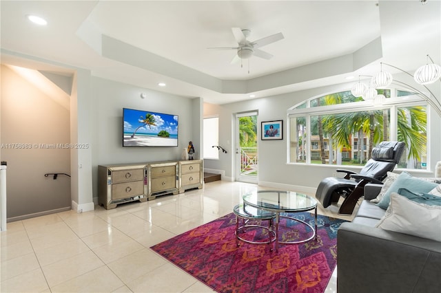 living room with baseboards, a ceiling fan, a tray ceiling, light tile patterned flooring, and recessed lighting