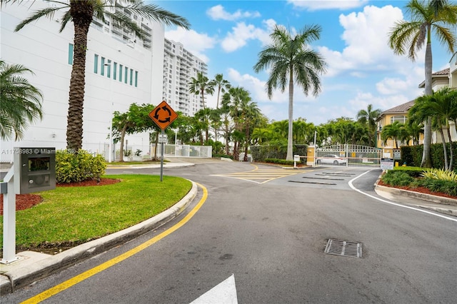 view of street featuring traffic signs, a gate, curbs, and a gated entry