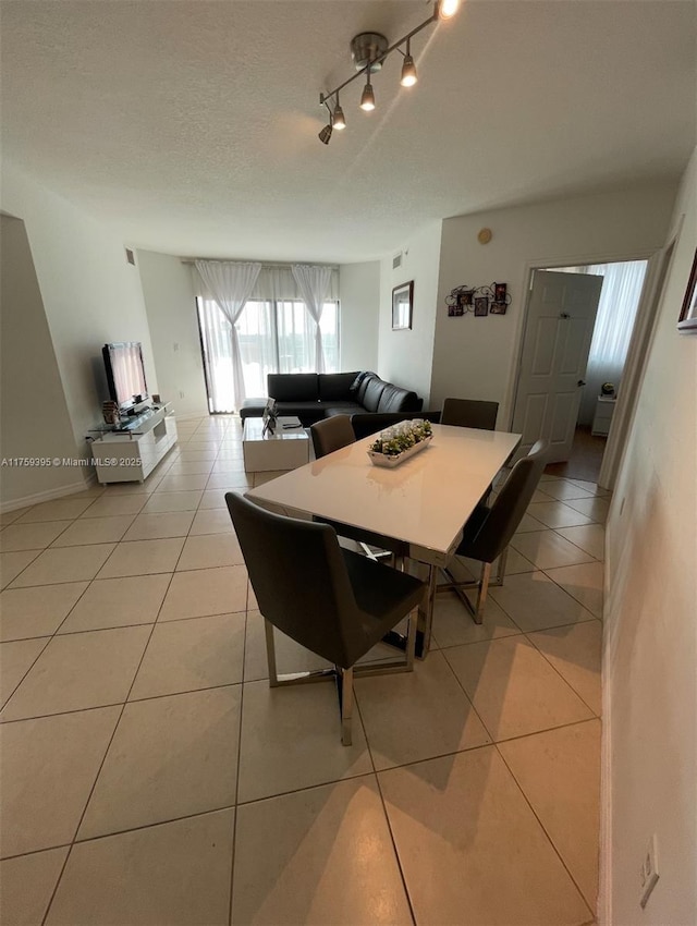 dining space with light tile patterned floors, a textured ceiling, and track lighting