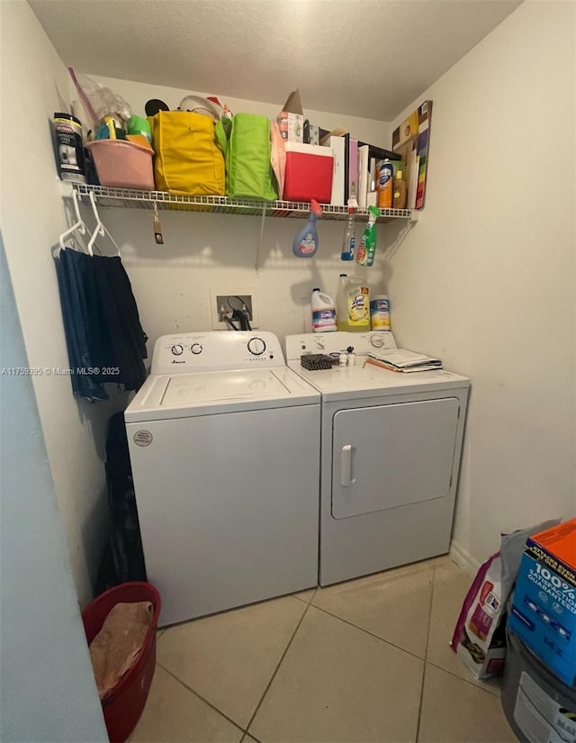 clothes washing area featuring laundry area, light tile patterned floors, and washer and clothes dryer