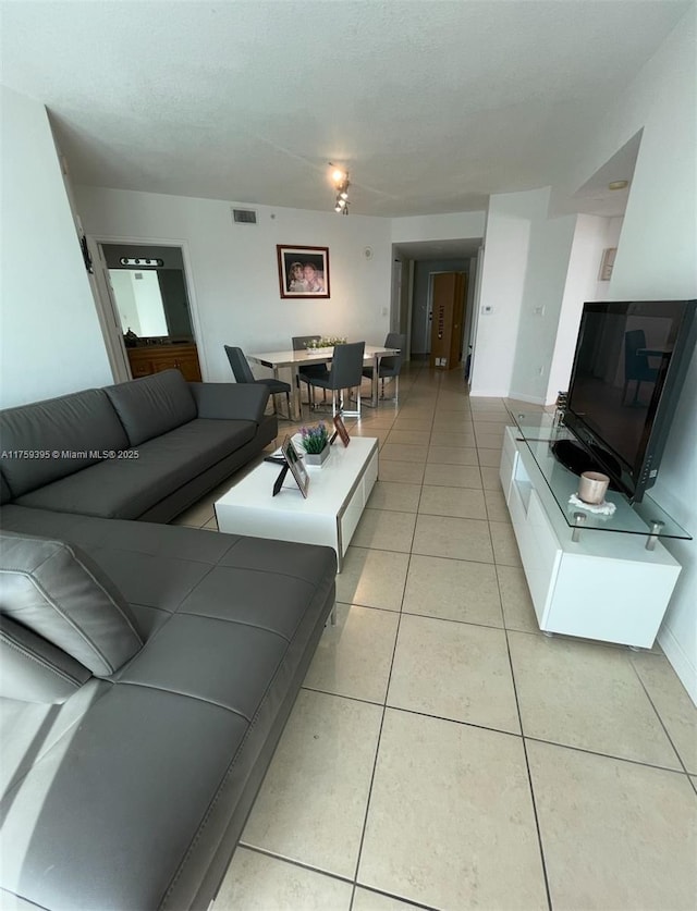 living area with light tile patterned floors, visible vents, and a textured ceiling