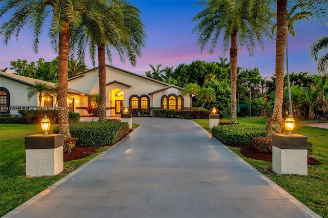 mediterranean / spanish home featuring stucco siding and a front yard