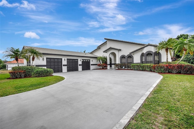 view of front of house with stucco siding, curved driveway, a front yard, and an attached garage