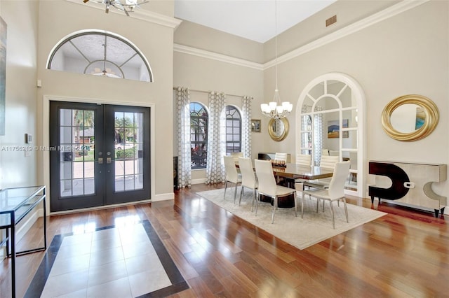 foyer with a chandelier, french doors, wood finished floors, a high ceiling, and baseboards