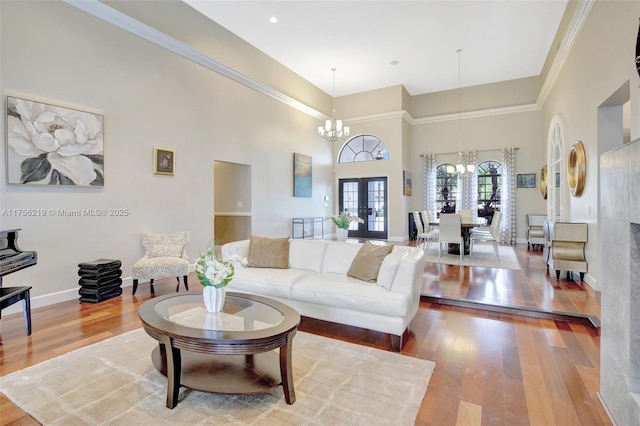 living room with a chandelier, french doors, wood finished floors, a high ceiling, and baseboards
