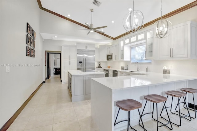 kitchen featuring stainless steel appliances, a breakfast bar area, a sink, crown molding, and a peninsula
