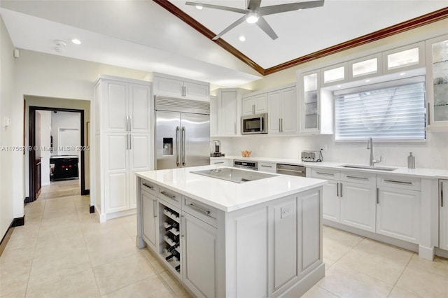 kitchen featuring appliances with stainless steel finishes, a sink, vaulted ceiling, a ceiling fan, and a center island