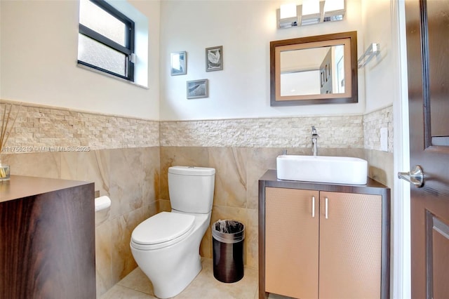 bathroom featuring tile walls, vanity, toilet, wainscoting, and tile patterned floors