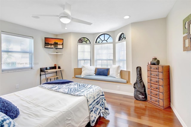bedroom with multiple windows, wood finished floors, baseboards, and recessed lighting