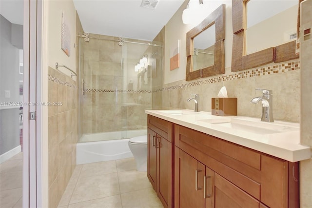 full bathroom with tile patterned flooring, tile walls, double vanity, toilet, and enclosed tub / shower combo