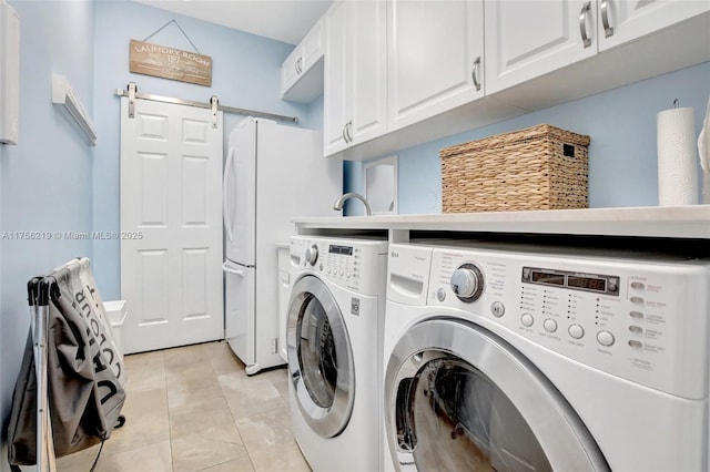 laundry room featuring cabinet space, washing machine and clothes dryer, a barn door, and light tile patterned floors