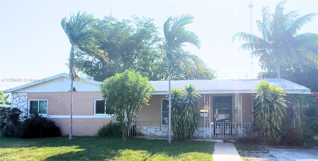 view of front of property featuring covered porch, a front lawn, and stucco siding