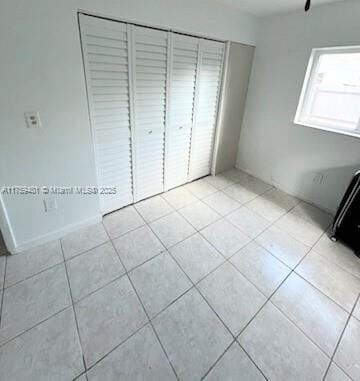 unfurnished bedroom with a closet and light tile patterned floors