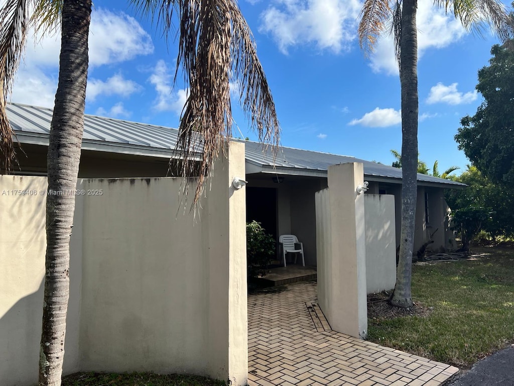 view of side of property with a standing seam roof, metal roof, and stucco siding