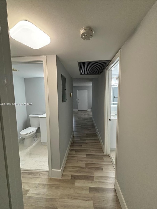 hall featuring baseboards, visible vents, and wood finished floors