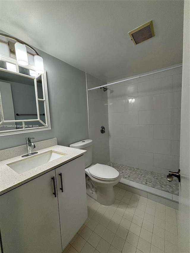 full bathroom featuring visible vents, vanity, toilet, and tiled shower