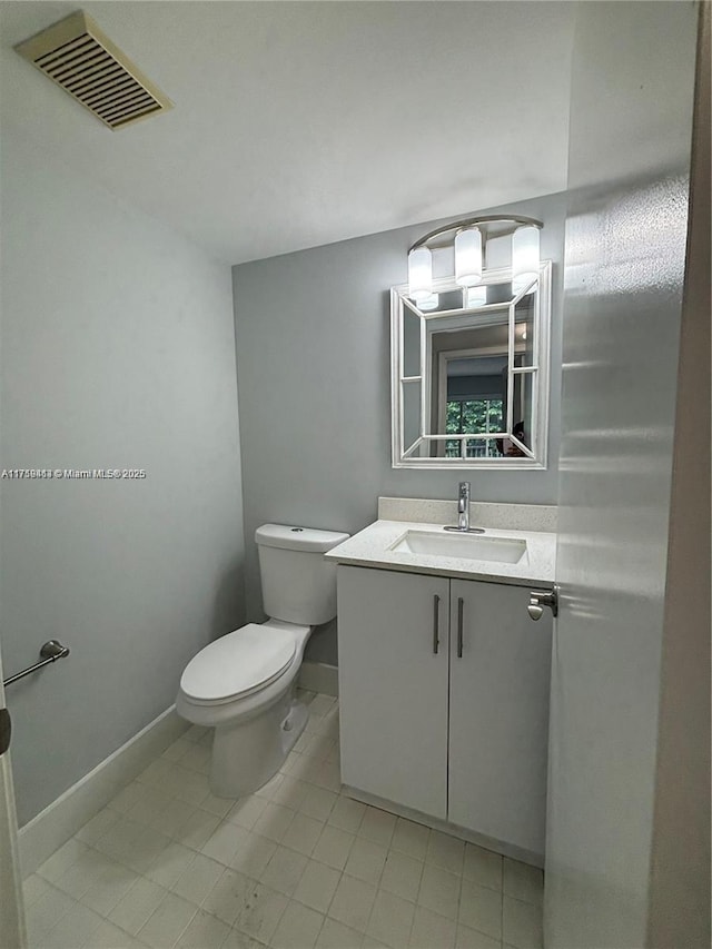 bathroom with toilet, vanity, visible vents, and baseboards