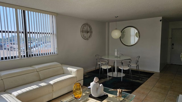 living area featuring tile patterned flooring, baseboards, and a textured ceiling