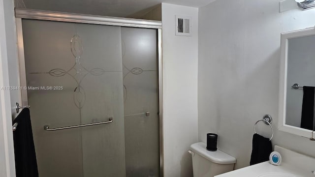 bathroom with toilet, a stall shower, vanity, and visible vents