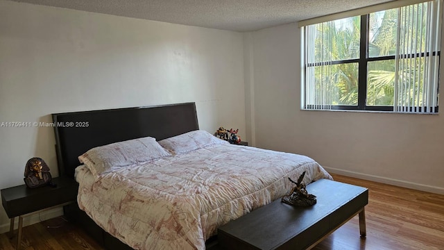 bedroom featuring a textured ceiling, wood finished floors, and baseboards