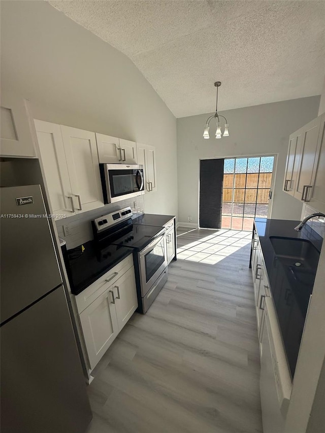 990 NE 212th Ter Unit 990-03, Miami, FL 33179 - kitchen with lofted ceiling, a notable chandelier, a sink, white cabinetry, and appliances with stainless steel finishes