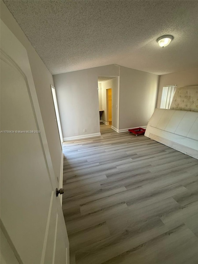 990 NE 212th Ter Unit 990-03, Miami, FL 33179 - unfurnished bedroom with a textured ceiling, wood finished floors, and baseboards
