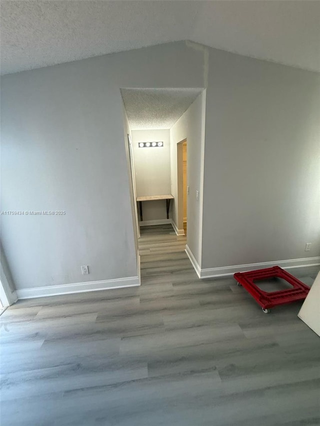 990 NE 212th Ter Unit 990-03, Miami, FL 33179 - interior space featuring vaulted ceiling, a textured ceiling, baseboards, and wood finished floors