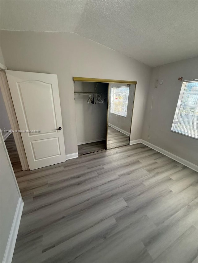 990 NE 212th Ter Unit 990-03, Miami, FL 33179 - unfurnished bedroom with lofted ceiling, a textured ceiling, a closet, and wood finished floors