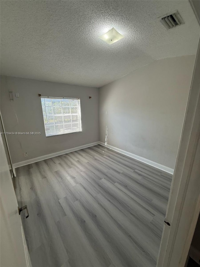 990 NE 212th Ter Unit 990-03, Miami, FL 33179 - empty room featuring visible vents, a textured ceiling, baseboards, and wood finished floors