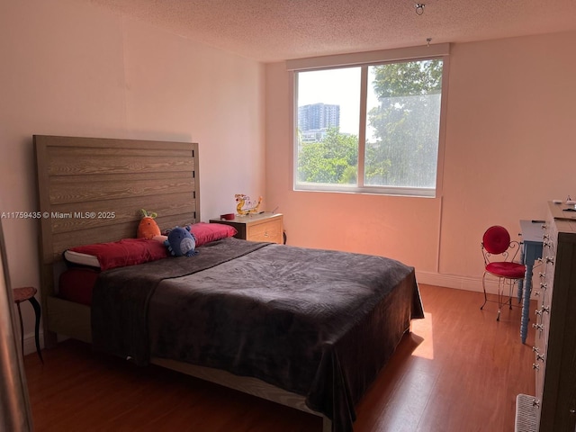 bedroom with a textured ceiling, wood finished floors, and visible vents