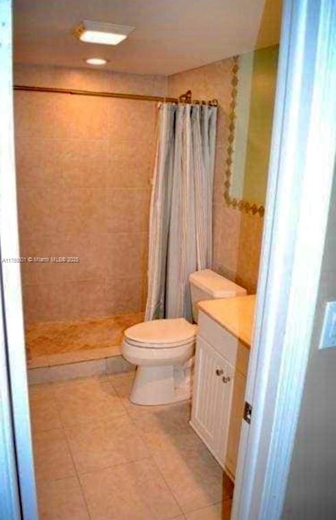 bathroom featuring a stall shower, tile patterned flooring, vanity, and toilet