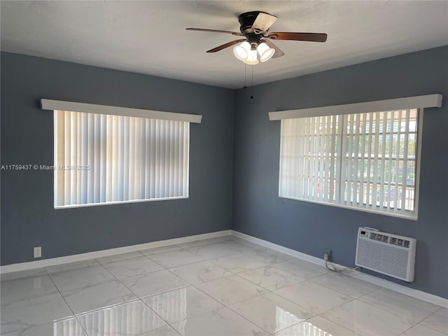 empty room featuring marble finish floor, ceiling fan, baseboards, and a wall mounted AC